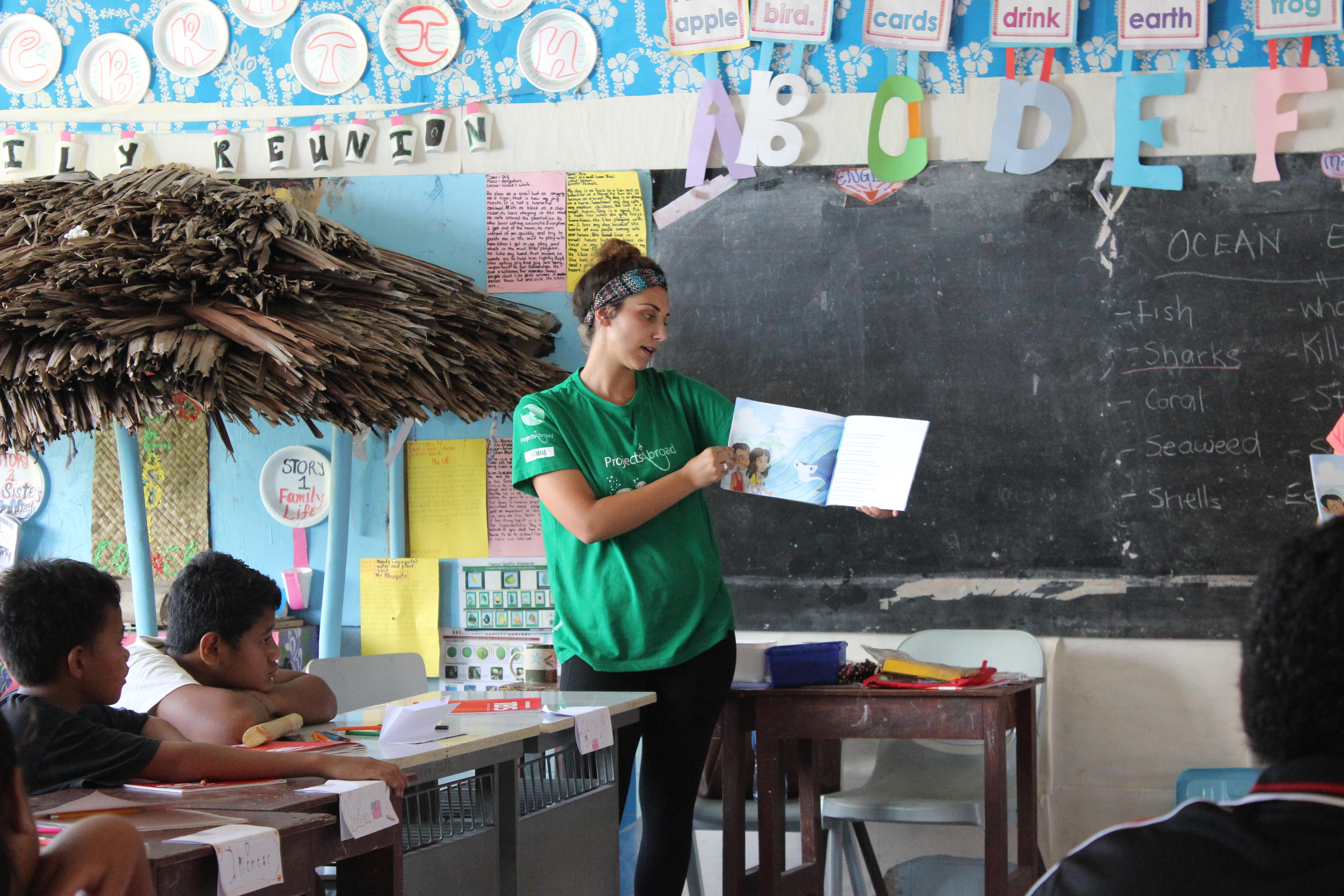 A Projects Abroad volunteer reads a book to a class in Samoa An alternative schoolies volunteer in Samoa reads a book for a class